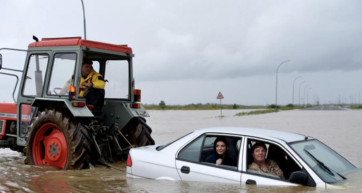 Sur une route inondée par la tempête Nils, un tracteur vient en aide à une voiture totalement bloquée